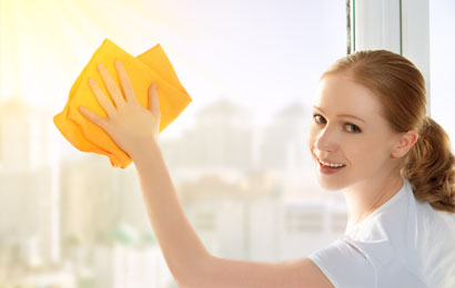 Smiling Young female cleaner wiping glass